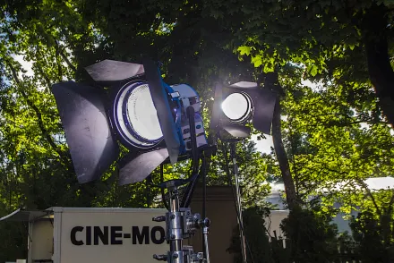 Zwei Filmscheinwerfer unter Bäumen, dahinter ein Technikwagen