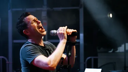 Nepo Fitz singt mit geschlossenen Augen ins Mikrofon, Bühnenlicht von rechts