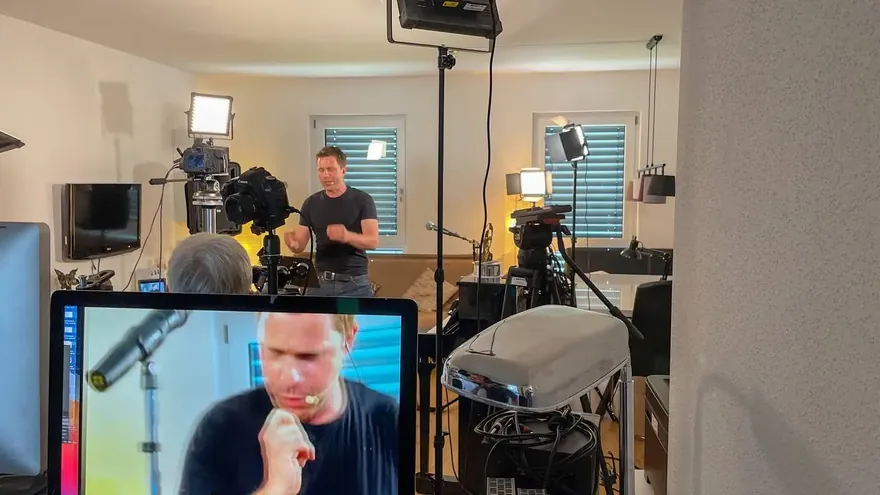 Monitor mit dem gesendeten Bild, dahinter Nepo Fitz live am Mikrofon, Kameras und Licht